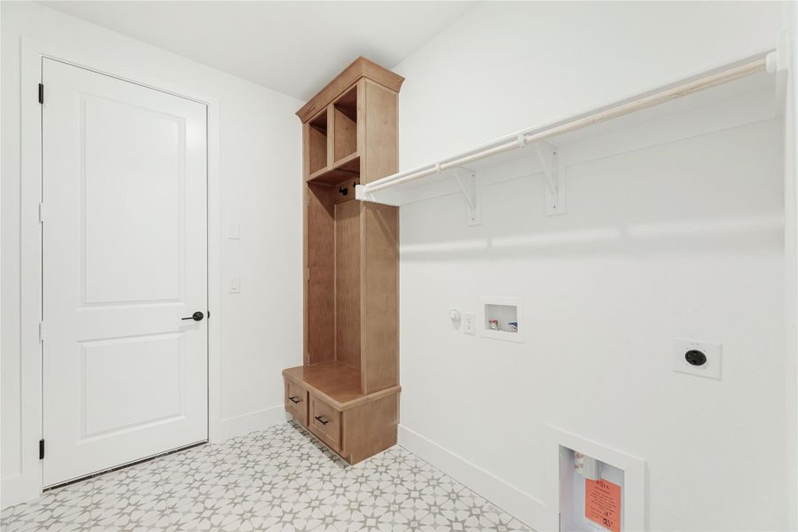 Laundry or mudroom with wood locker cabinet, wall-mounted clothing rod, and patterned tile floor