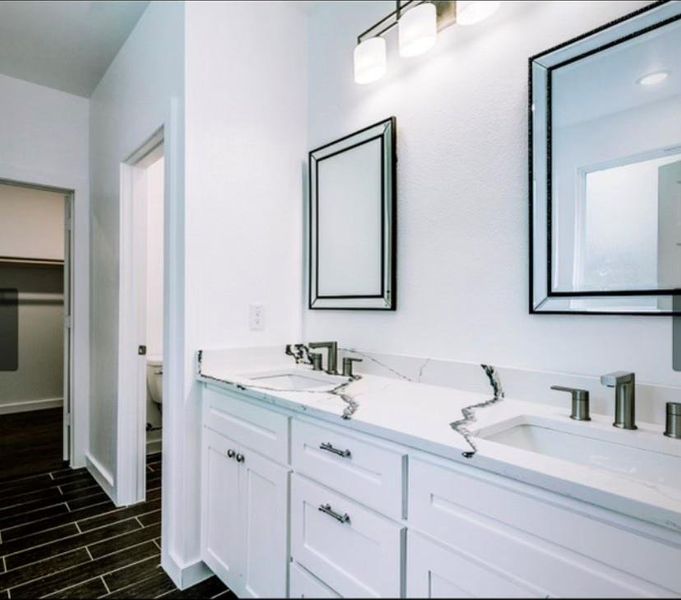 Bathroom with toilet, oversized vanity, and dual sinks