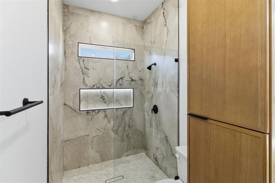 Full bath featuring a marble finish shower and toilet