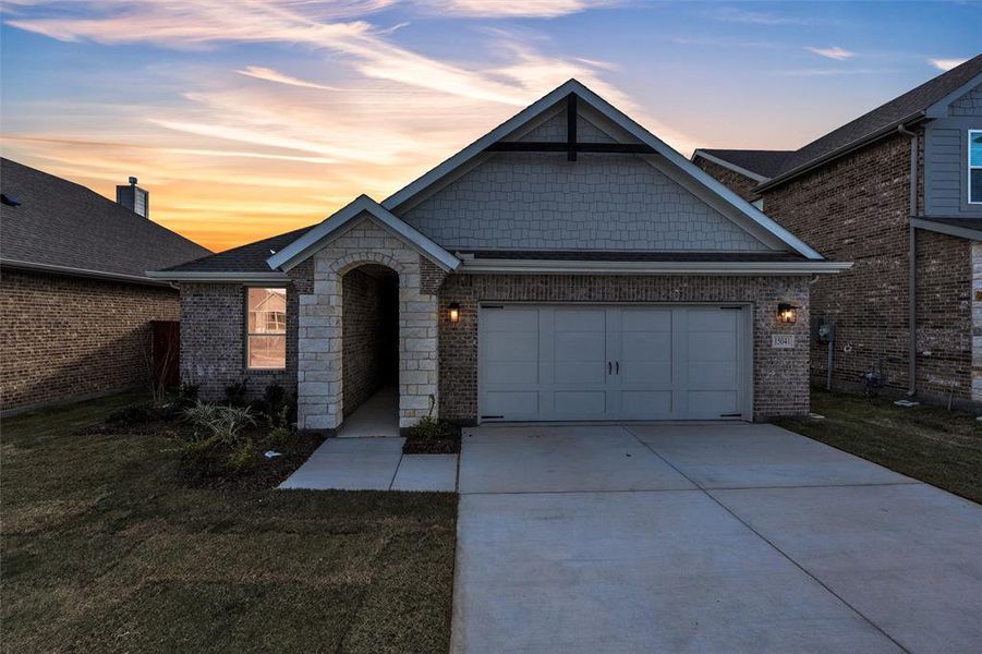 View of front of home with driveway, a garage, a front yard, and brick siding