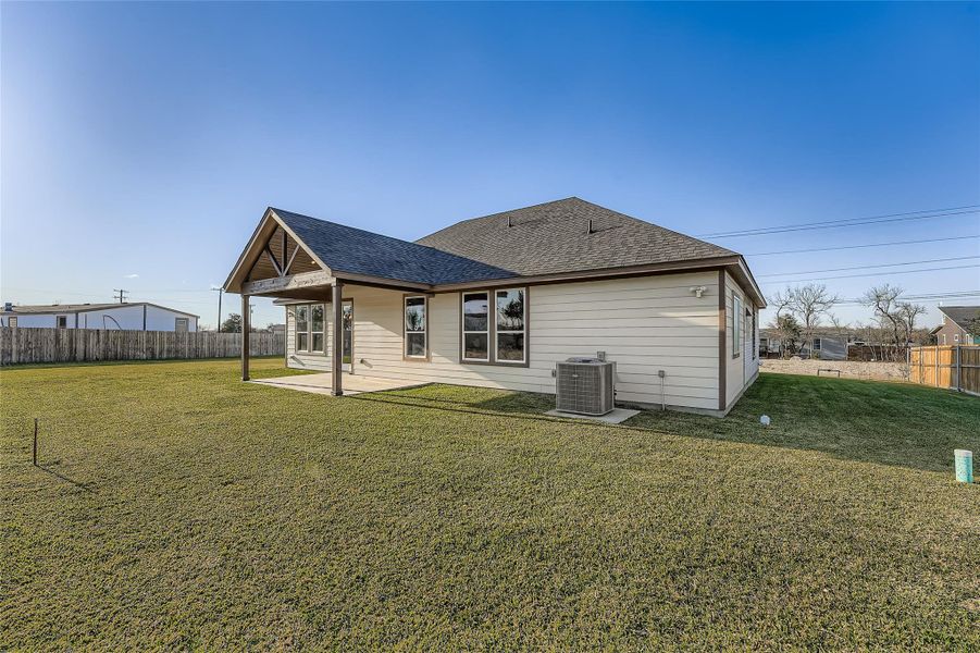 Rear view of property featuring a patio, a fenced backyard, and a shingled roof