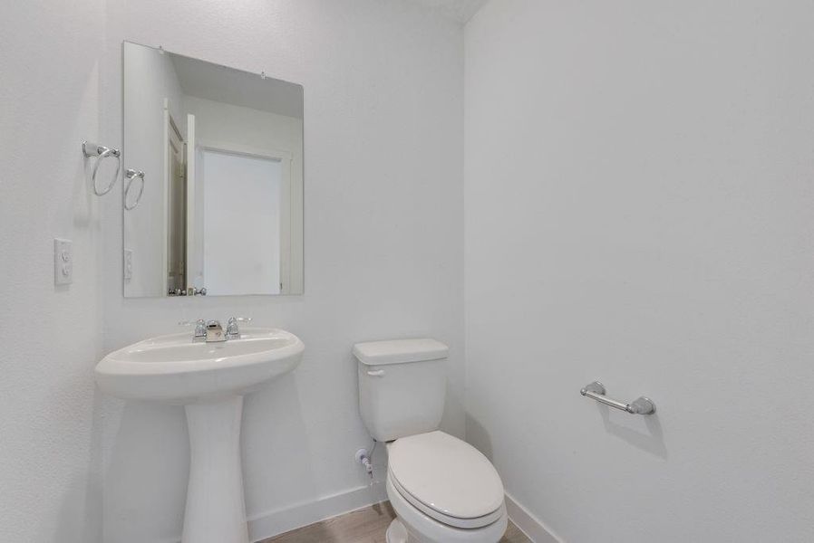 Half bathroom with baseboards and wood finished floors Half bathroom with baseboards and wood finished floors