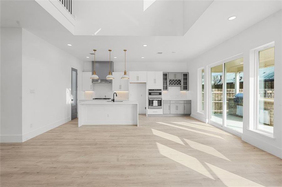 Kitchen with light countertops, open floor plan, decorative light fixtures, an island with sink, and light wood-type flooring Kitchen with light countertops, open floor plan, decorative light fixtures, an island with sink, and light wood-type flooring