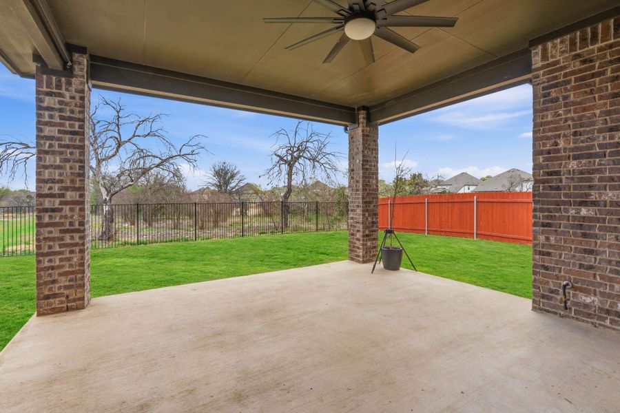 Fenced backyard with a ceiling fan and a patio