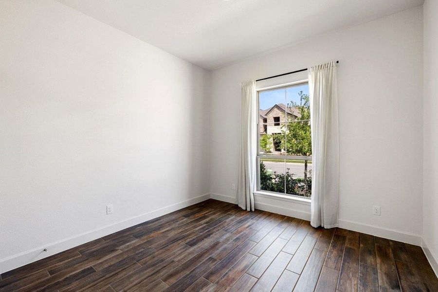 Rich hardwood-style flooring extends across this versatile room, offering an inviting blank canvas.