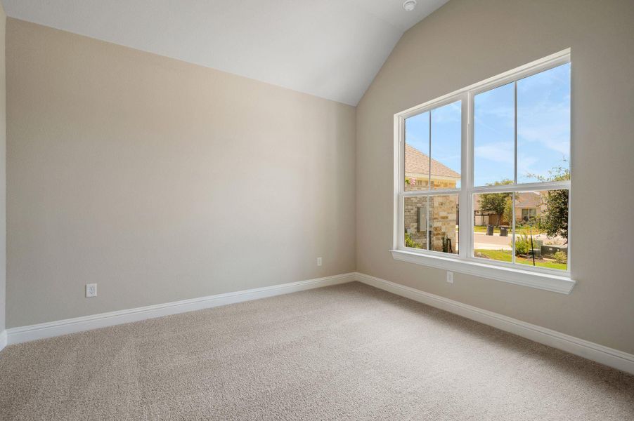 Carpeted empty room featuring vaulted ceiling and baseboards