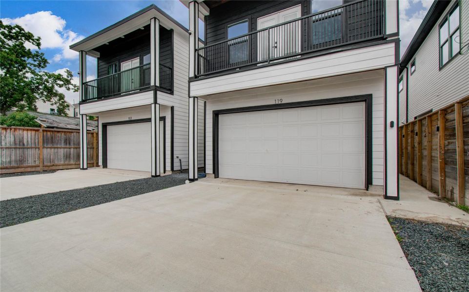 Modern townhouse with a sleek exterior, featuring a balcony and a two-car garage. The design is contemporary with clean lines, offering ample driveway space and private gated entrances.