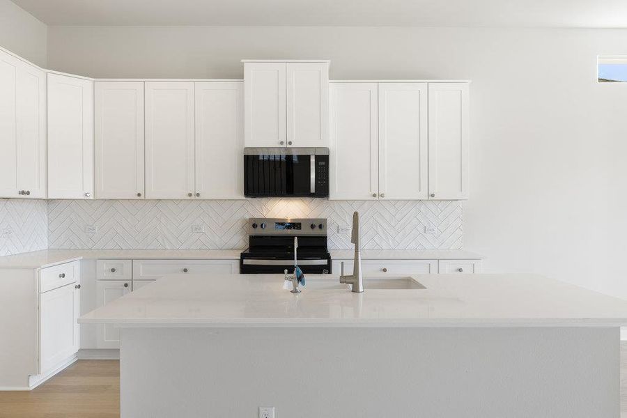 Kitchen with backsplash, white cabinets, appliances with stainless steel finishes, and light stone counters