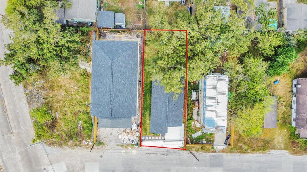 This aerial photo showcases a residential area adjacent to a busy highway, with a mix of single-family homes. The marked property is a two-story house with a fenced yard, located near urban amenities and transportation links.