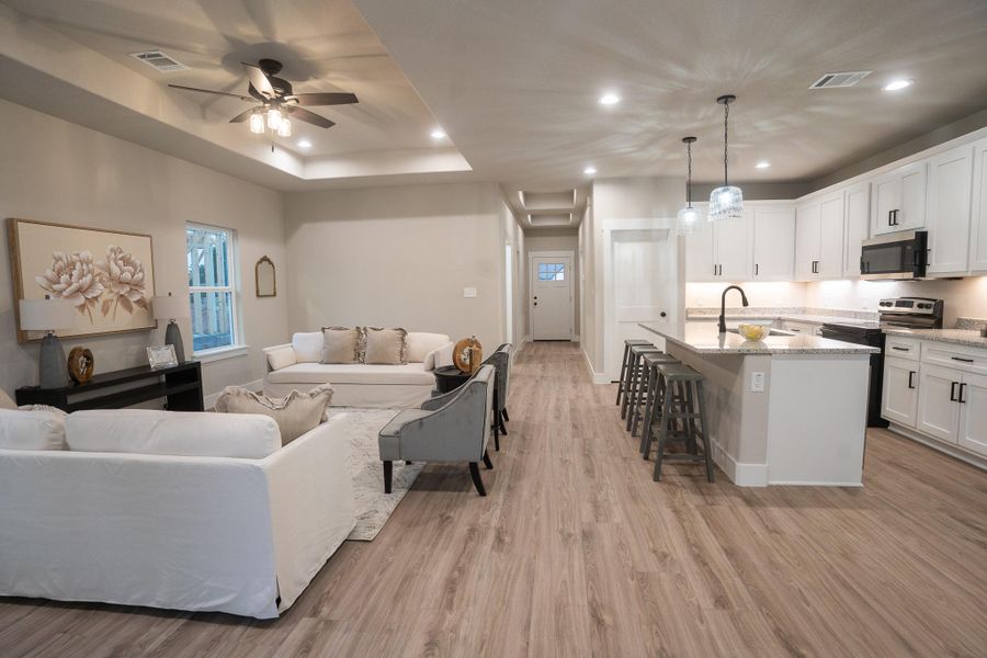 Living area with light wood-style floors, ceiling fan, recessed lighting, and a raised ceiling