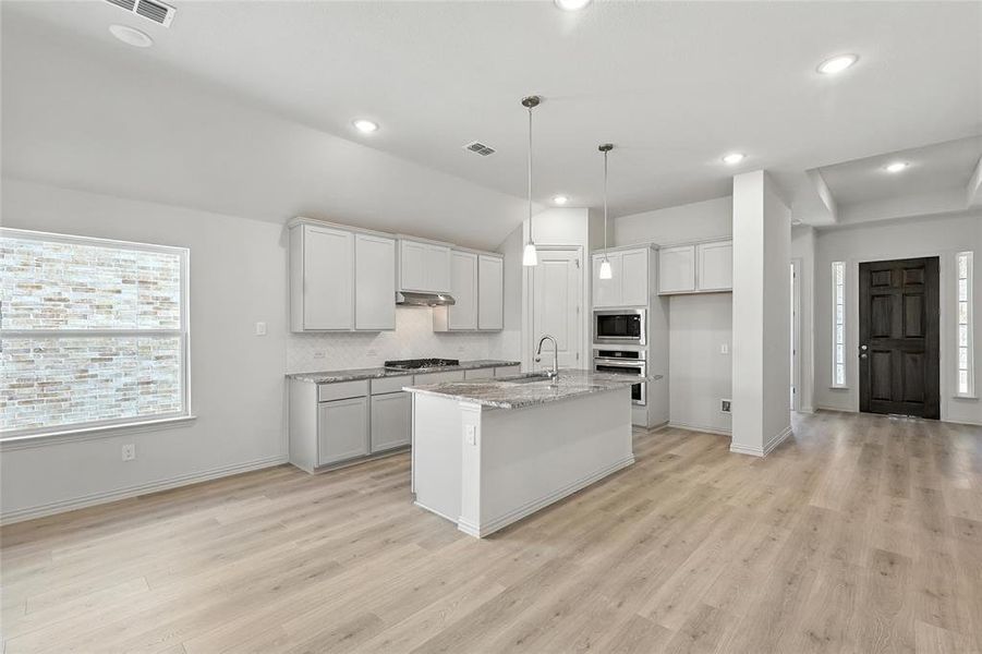 Kitchen featuring appliances with stainless steel finishes, light wood-style flooring, under cabinet range hood, a center island with sink, and recessed lighting Kitchen featuring appliances with stainless steel finishes, light wood-style flooring, under cabinet range hood, a center island with sink, and recessed lighting