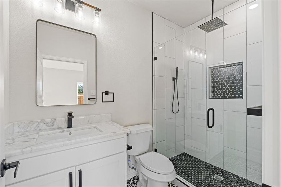 Bathroom featuring vanity, toilet, and an enclosed shower