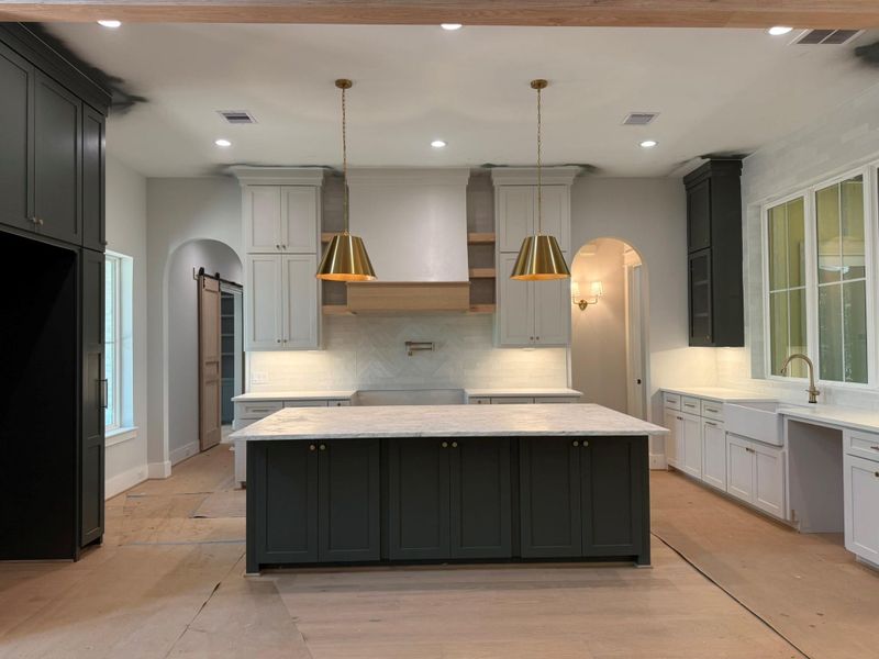 Kitchen with a kitchen island, arched walkways, a barn door, decorative backsplash, and recessed lighting
