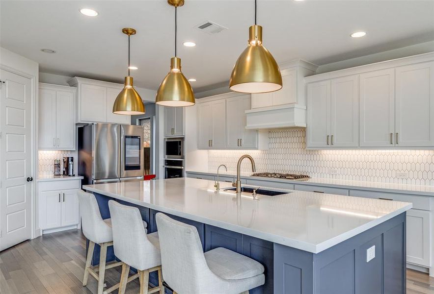 Kitchen featuring light wood-style floors, white cabinetry, a breakfast bar area, appliances with stainless steel finishes, and tasteful backsplash