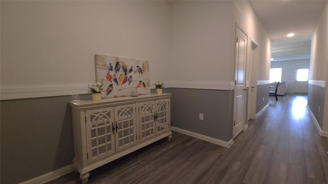 Hallway featuring wood-finish flooring, two-tone wall paneling with crown molding, and recessed lighting
