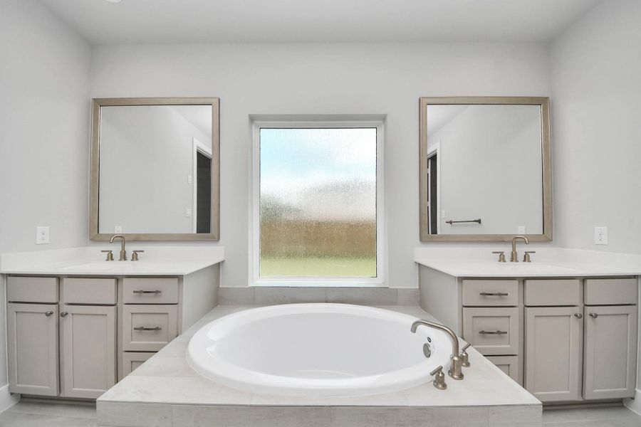 Indulge in a spa-like retreat within the confines of this primary bathroom. Delight in a spacious walk-in shower enveloped in stylish tile surround, unwind in a separate garden tub adorned with custom detailing. Indulge in a spa-like retreat within the confines of this primary bathroom. Delight in a spacious walk-in shower enveloped in stylish tile surround, unwind in a separate garden tub adorned with custom detailing.