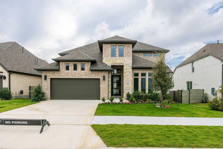 View of front of house with brick siding, roof with shingles, concrete driveway, and stone siding