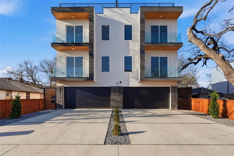 Contemporary home featuring brick siding, a balcony, driveway, and a garage Contemporary home featuring brick siding, a balcony, driveway, and a garage