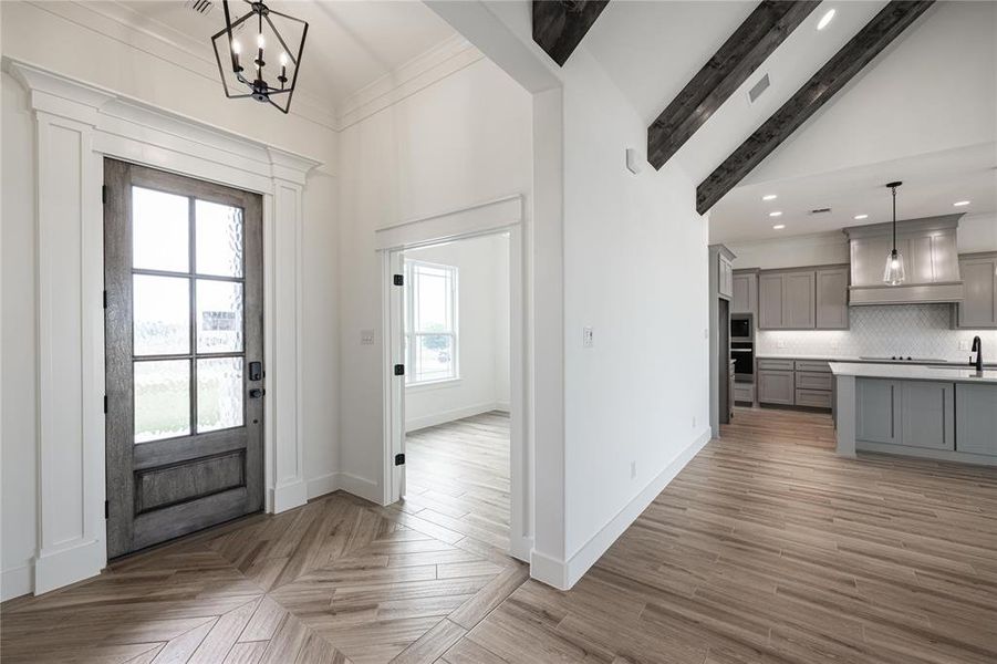 Foyer entrance featuring light hardwood / wood-style floors, beamed ceiling, crown molding, sink, and a chandelier