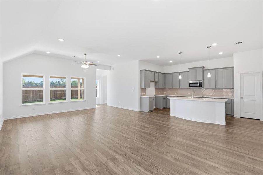 Open-concept living space featuring wood-finish flooring, vaulted ceilings with a ceiling fan, and recessed lighting