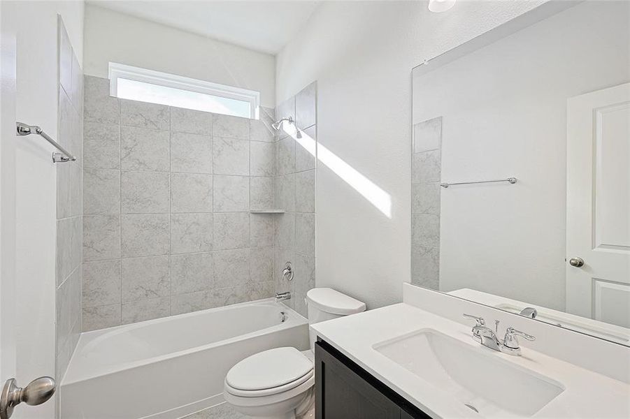 Full bathroom featuring vanity, tiled shower / bath combo, and toilet