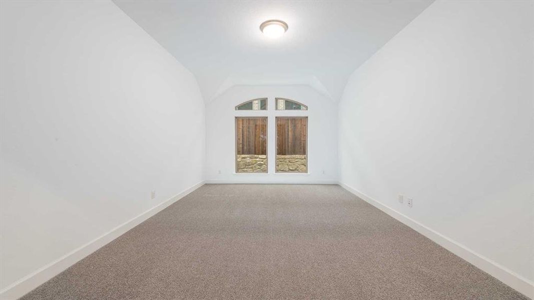 Unfurnished room featuring carpet floors and vaulted ceiling