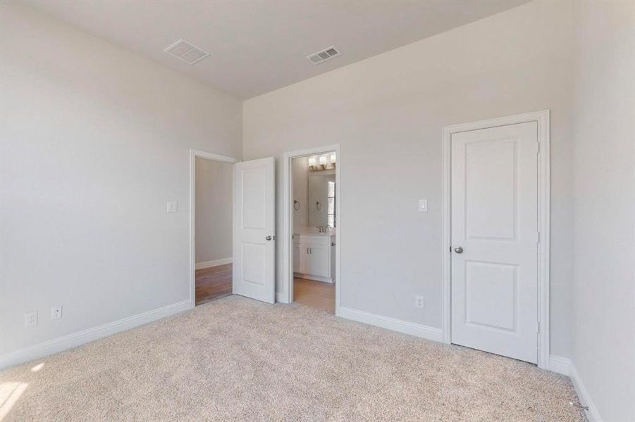 Unfurnished bedroom with light colored carpet and ensuite bath