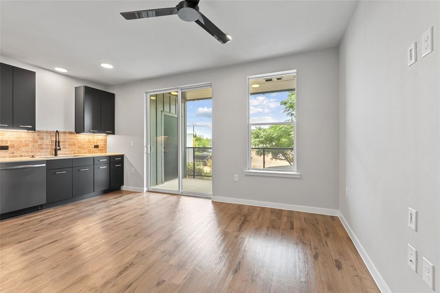 Kitchen featuring dishwasher, tasteful backsplash, light wood-style flooring, dark cabinets, and light countertops