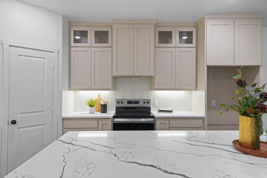 Contemporary kitchen featuring light-toned cabinetry, a built-in range, and a white hexagonal tile backsplash Contemporary kitchen featuring light-toned cabinetry, a built-in range, and a white hexagonal tile backsplash