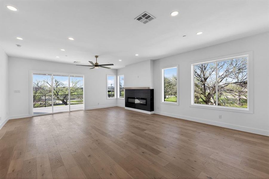 Unfurnished living room featuring a glass covered fireplace, dark wood-style flooring, and recessed lighting