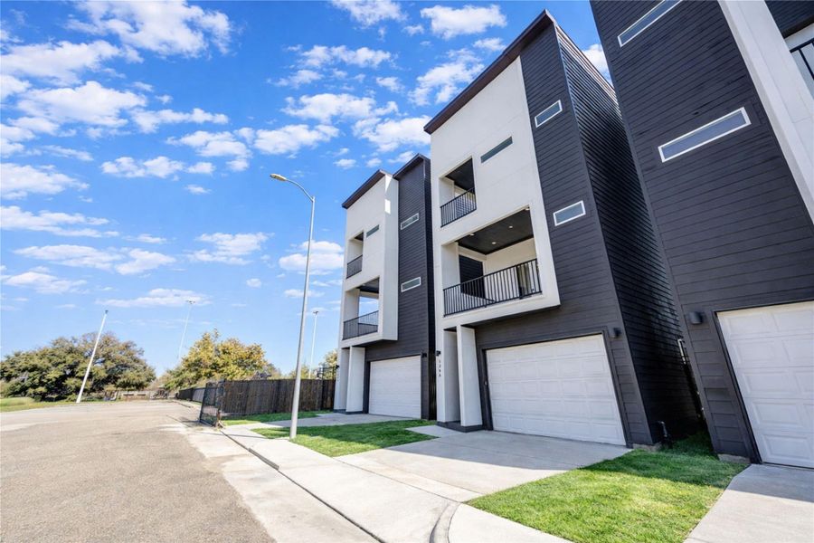 Modern townhomes with a sleek, contemporary design featuring three stories, balconies, and attached garages.