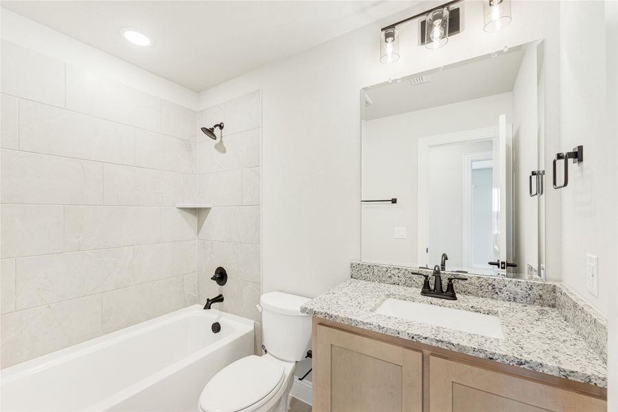 Bathroom with tiled tub-shower combo, granite vanity, and dark bronze fixtures