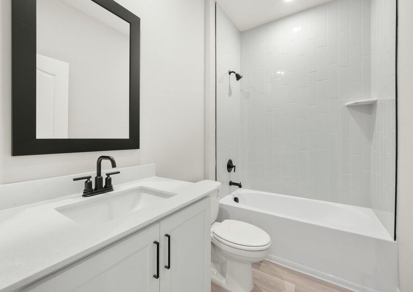 This secondary bathroom features a large vanity and beautifully tiled shower