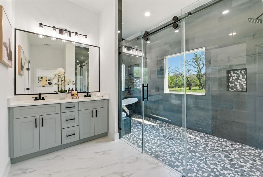 Primary bathroom featuring a freestanding tub, a shower stall, and double vanity