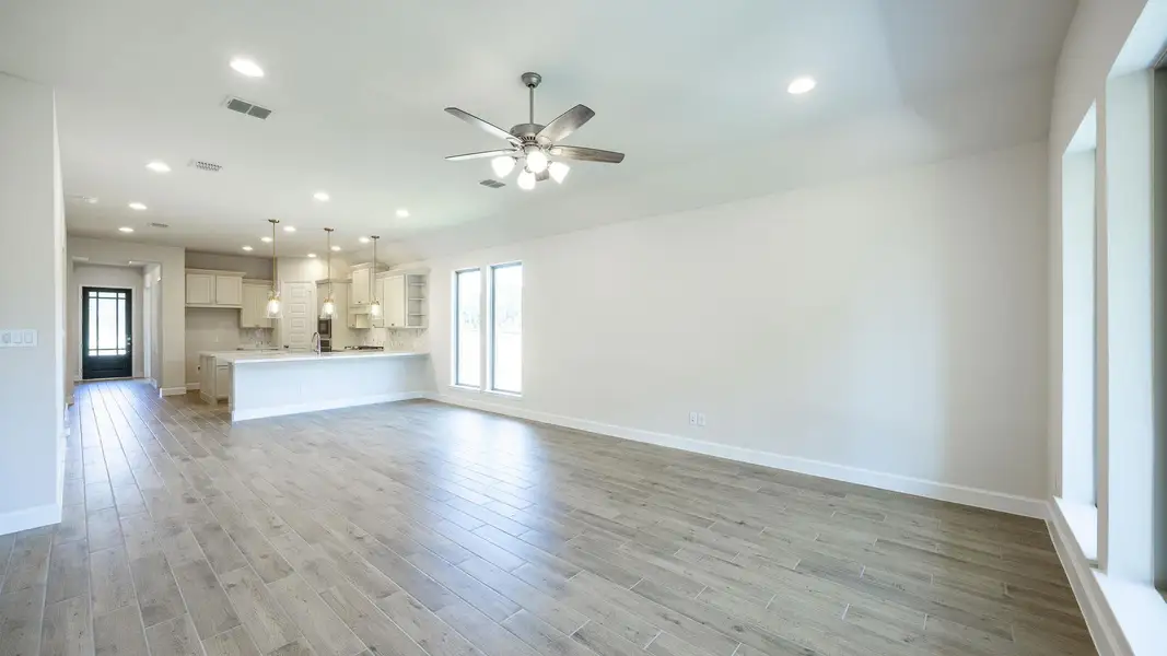 Unfurnished living room with plenty of natural light, a ceiling fan, light wood-type flooring, and recessed lighting Unfurnished living room with plenty of natural light, a ceiling fan, light wood-type flooring, and recessed lighting