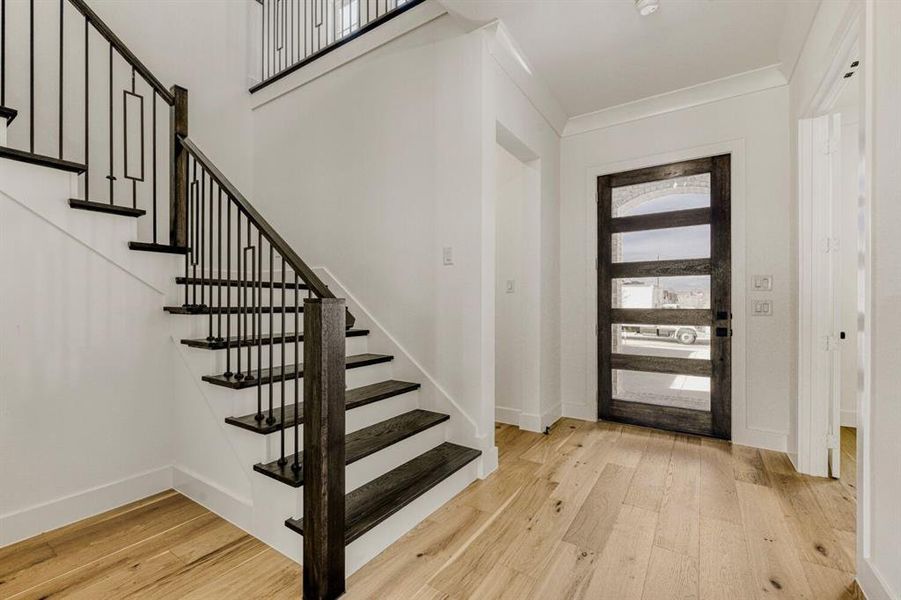 Foyer featuring light wood-type flooring and ornamental molding