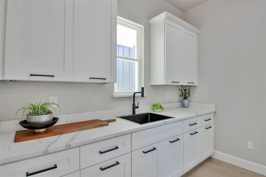 Kitchen featuring white cabinetry, light stone countertops, and light wood-type flooring Kitchen featuring white cabinetry, light stone countertops, and light wood-type flooring