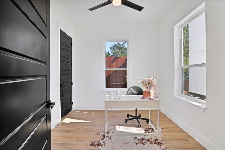 Home office with healthy amount of natural light, a ceiling fan, baseboards, and light wood-style flooring