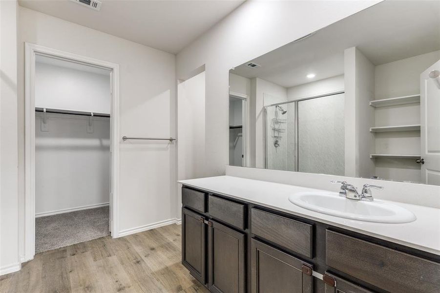 Bathroom vanity featuring a single basin sink, chrome faucet, and expansive mirror Bathroom vanity featuring a single basin sink, chrome faucet, and expansive mirror