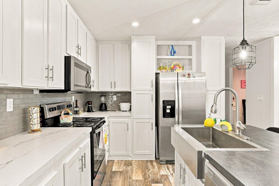 Modern cabinetry and recessed lighting complement the sleek solid-surface countertops in this kitchen.