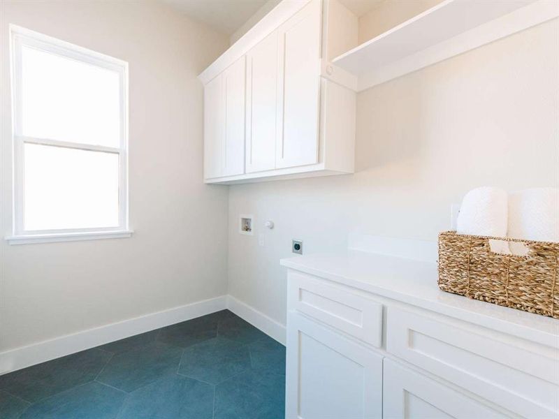 Laundry area with hookup for a washing machine, cabinets, hookup for an electric dryer, and dark tile patterned flooring