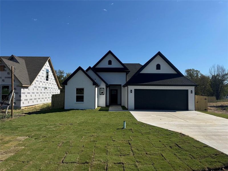 View of front of home with a garage and a front lawn