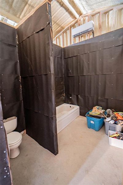 Full bathroom with vaulted ceiling, a wall mounted air conditioner, and a bath