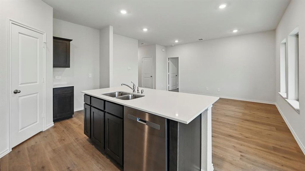 Kitchen featuring stainless steel dishwasher, a center island with sink, recessed lighting, light wood-style floors, and open floor plan