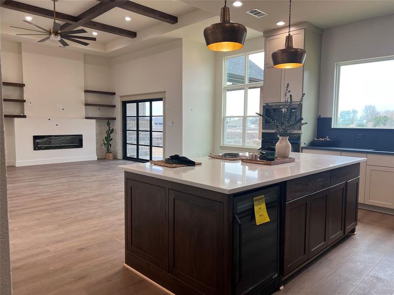 Kitchen featuring coffered ceiling, a center island, hanging light fixtures, light hardwood / wood-style flooring, and white cabinets