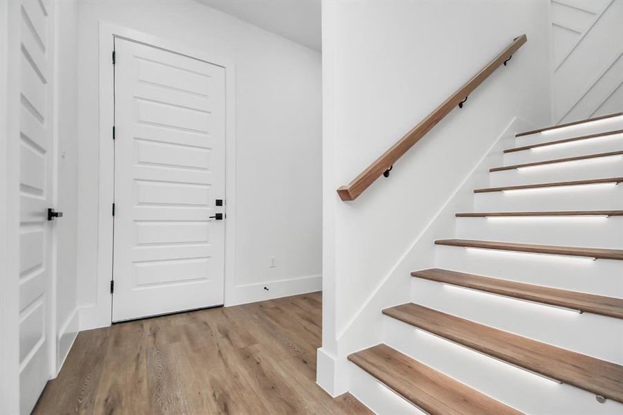 Entry to the second floor  at the front of the home featuring lighting under each staircase.