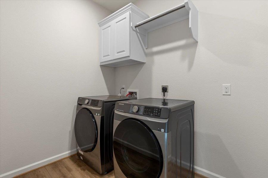 Washroom featuring light wood finished floors, washer and clothes dryer, and cabinet space Washroom featuring light wood finished floors, washer and clothes dryer, and cabinet space