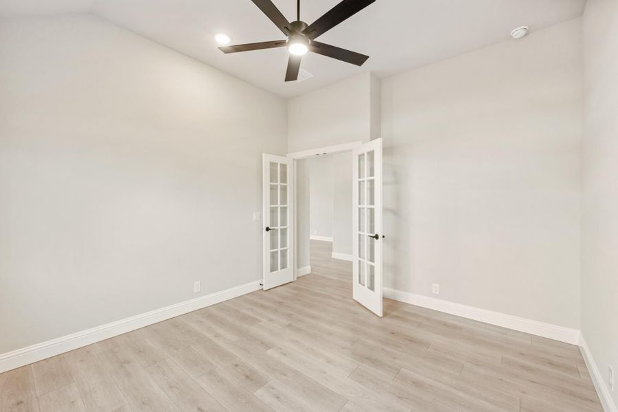 Empty room with light wood floors, ceiling fan, and white French doors Empty room with light wood floors, ceiling fan, and white French doors