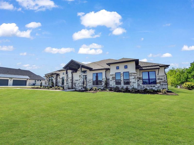 View of front facade with a front yard, stucco siding, and stone siding View of front facade with a front yard, stucco siding, and stone siding