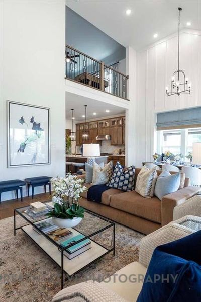 Living room featuring a chandelier, a towering ceiling, recessed lighting, and wood finished floors Living room featuring a chandelier, a towering ceiling, recessed lighting, and wood finished floors